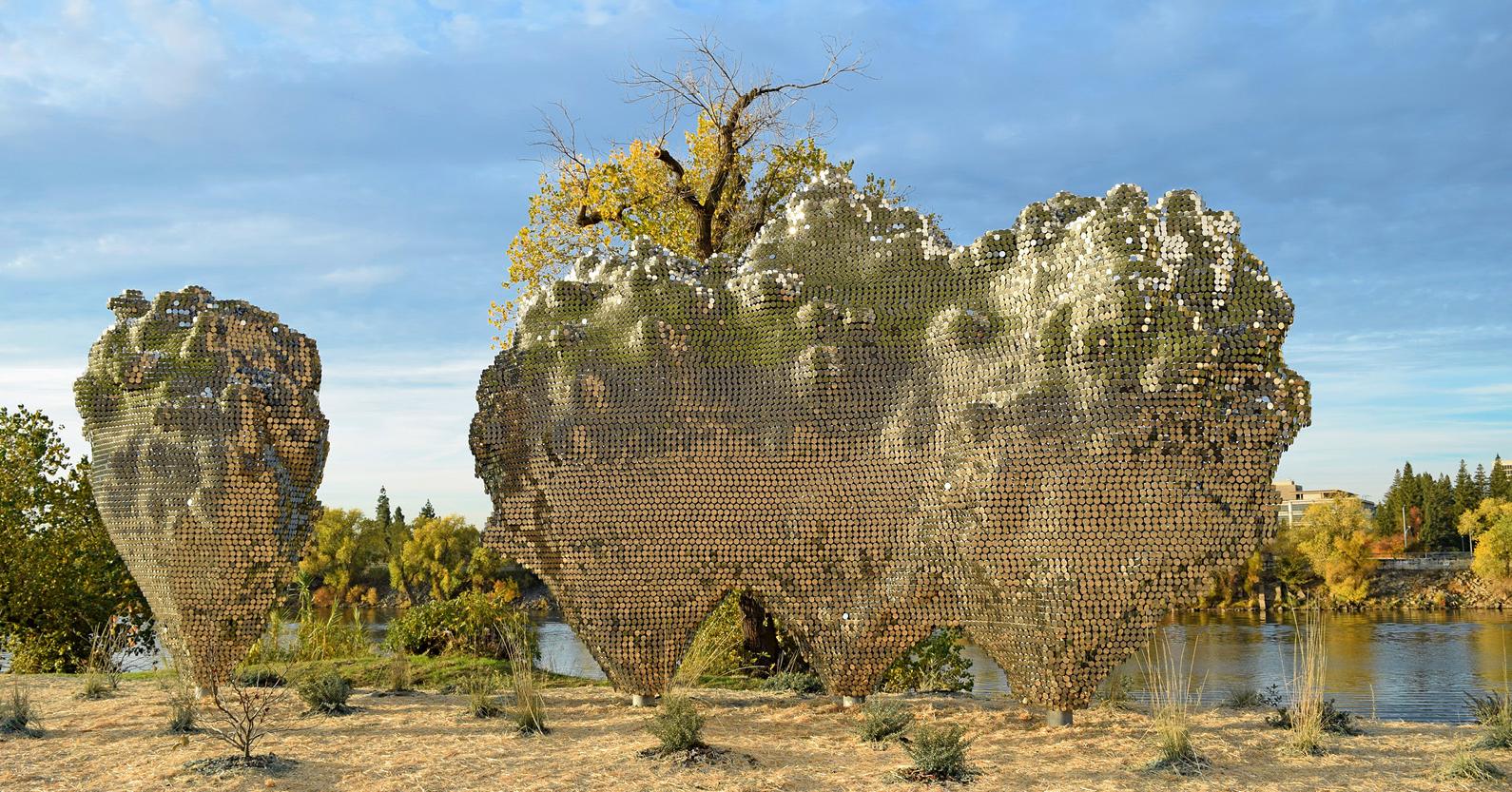 A cloud spaced sculpture made of many tiny metal mirrors twinkles on a bright day.